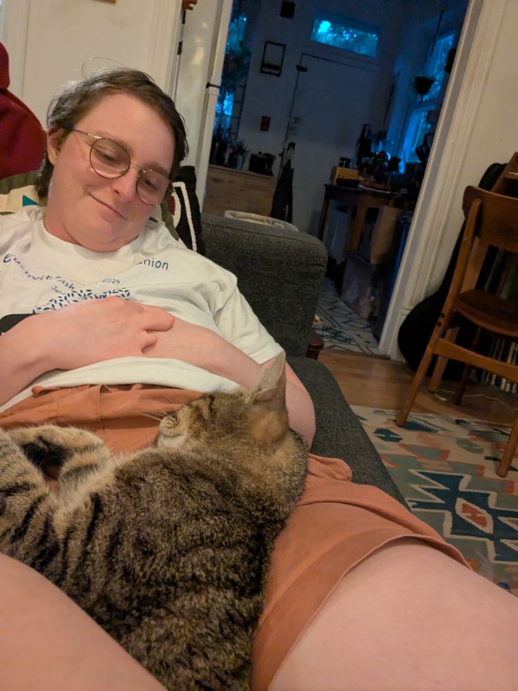 This sweet cat is nestled in the crook of Finn's legs and Finn is looking lovingly down at her