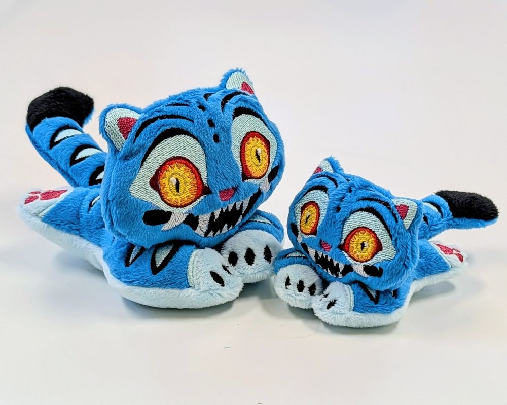 Photo of two plushies of Derpy the tiger from Kpop Demon Hunters. The one on the left is pretty big while the one on the right is tiny.