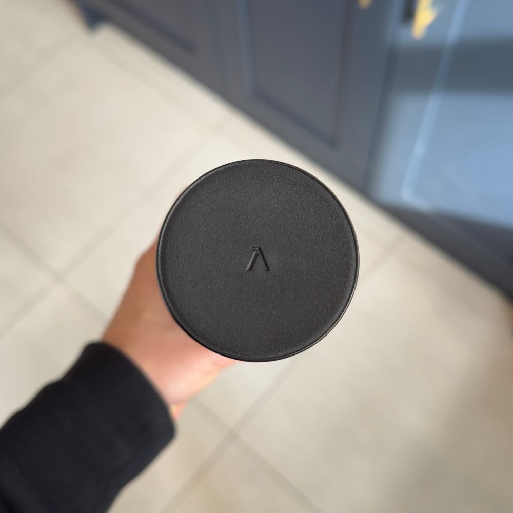 The lid of a black LARQ water bottle, which shows only the A of their logo. It has similarities to Aphex Twin’s more abstract “A” logo.