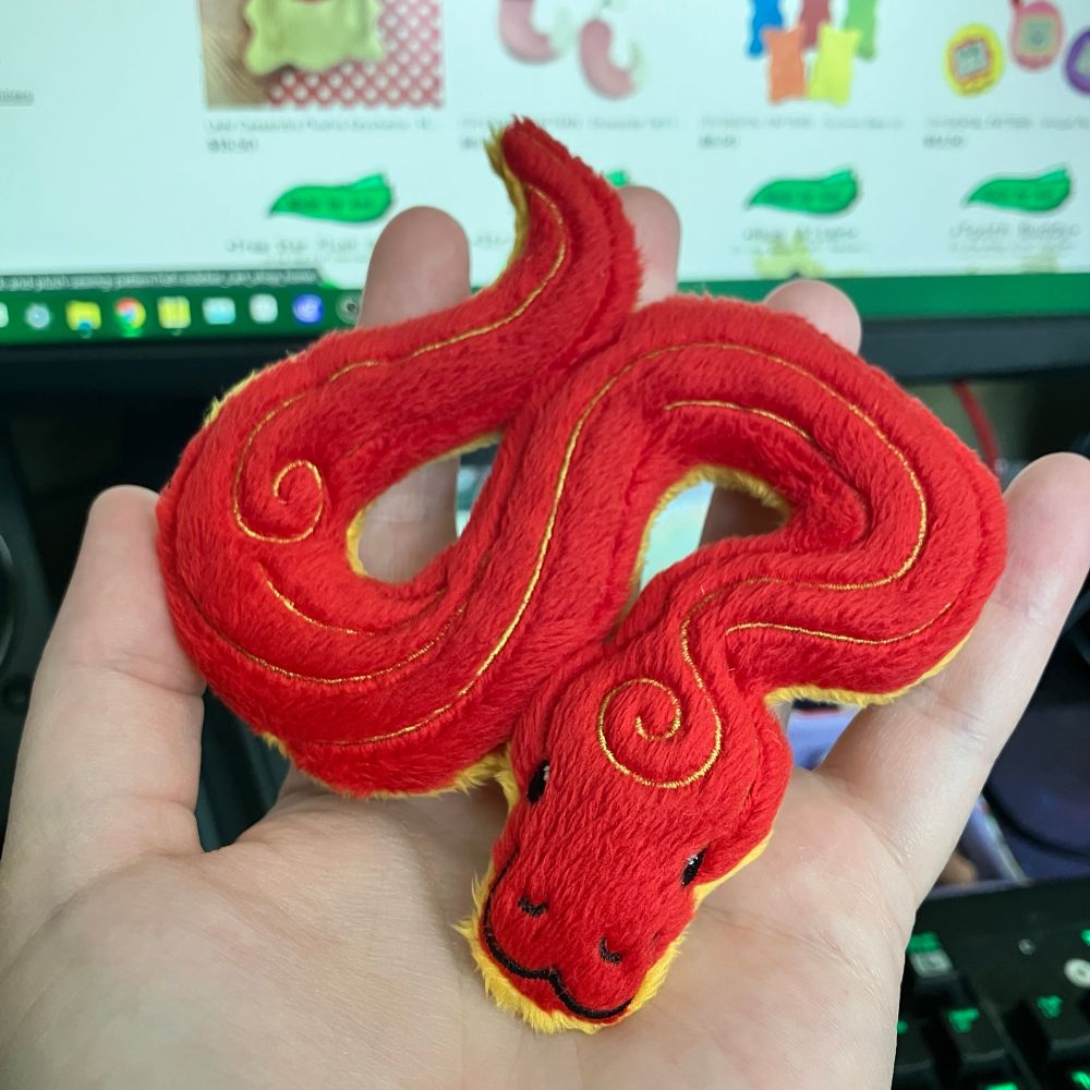 Palm sized red and gold plushie snake celebrating the lunar new year 