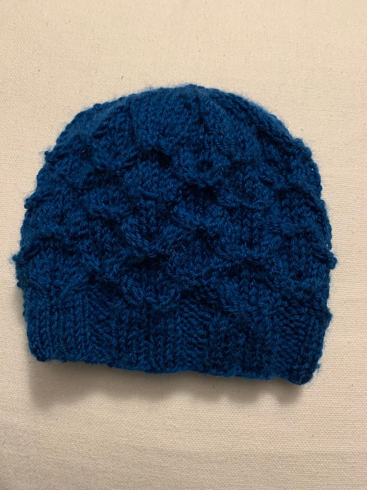 A navy blue honeycomb cabled hat on a white background. 