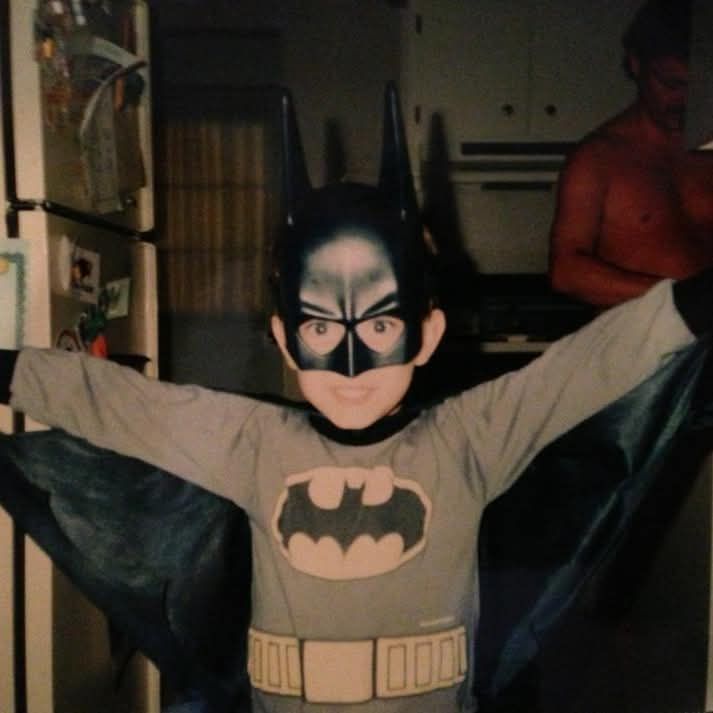 An image of myself in the kitchen when I was maybe 4 years old dressed as Batman. My arms spread out. 