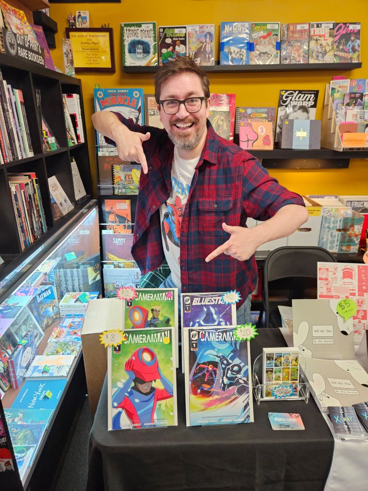 Colorful man in bookstore points at his books.