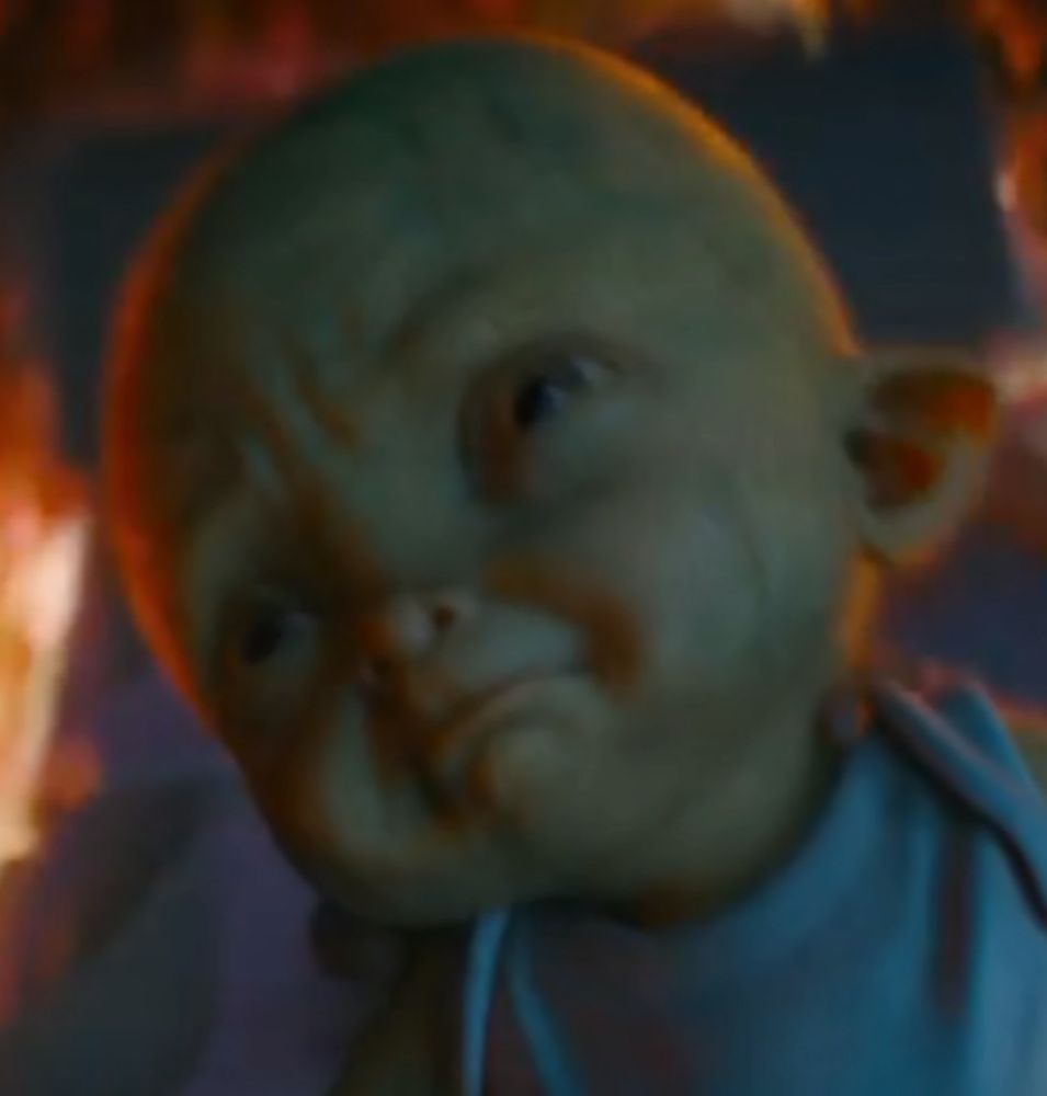 A closeup on a weird green baby's face