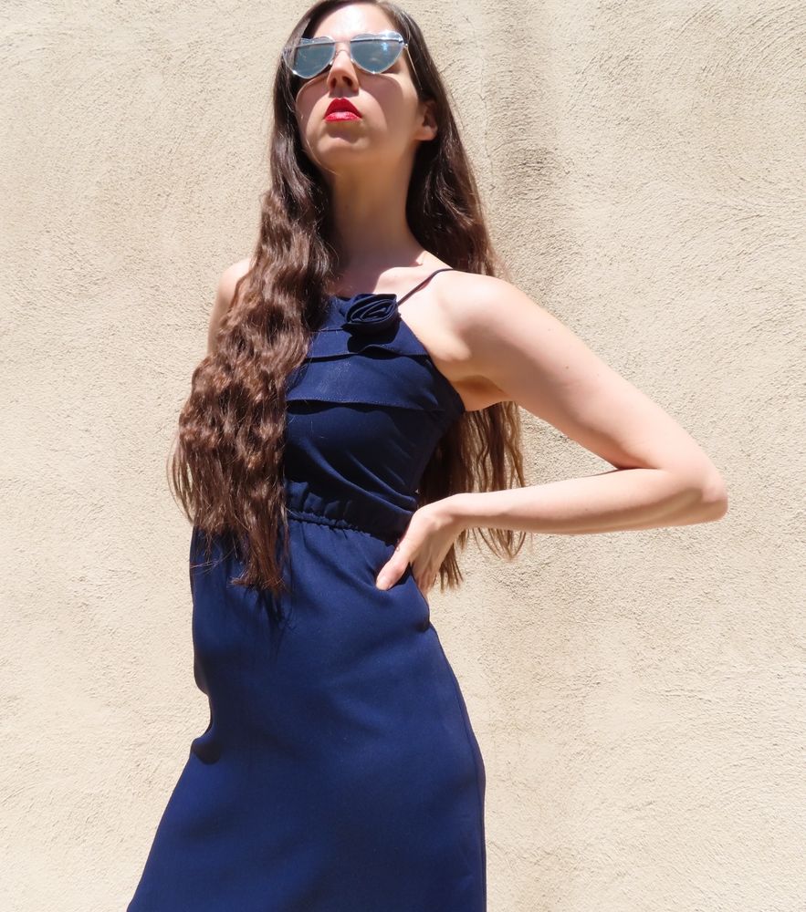 White brunette femme in heart-shaped sunglasses and a navy sleeveless dress