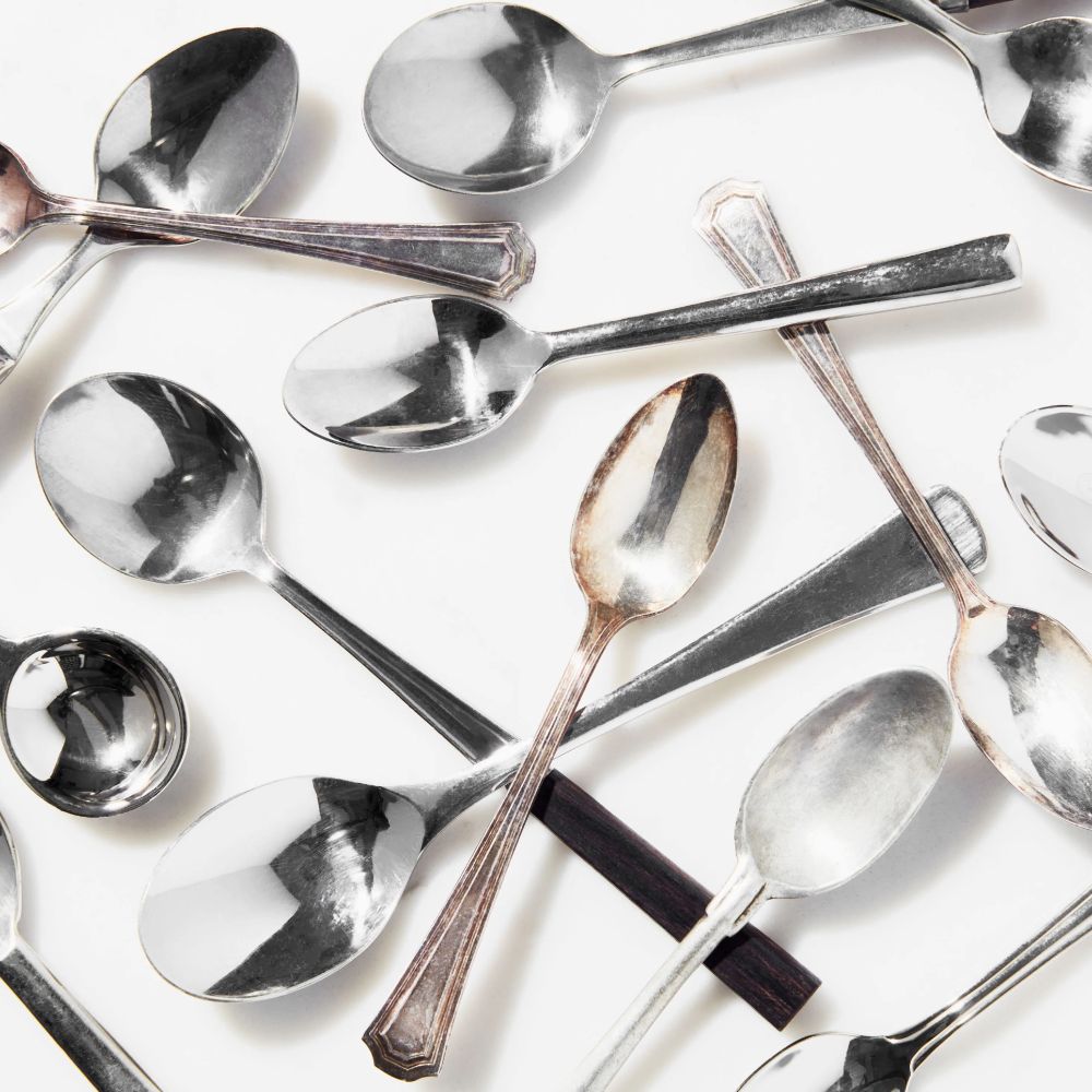 A whole bunch of spoons on a white tablecloth