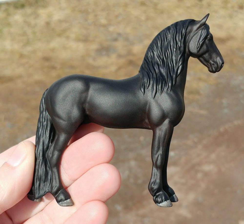A 1:32 scale Breyer Django (Friesian) model horse repainted to a solid matte black with subtle brown undertones. Right side pictured.