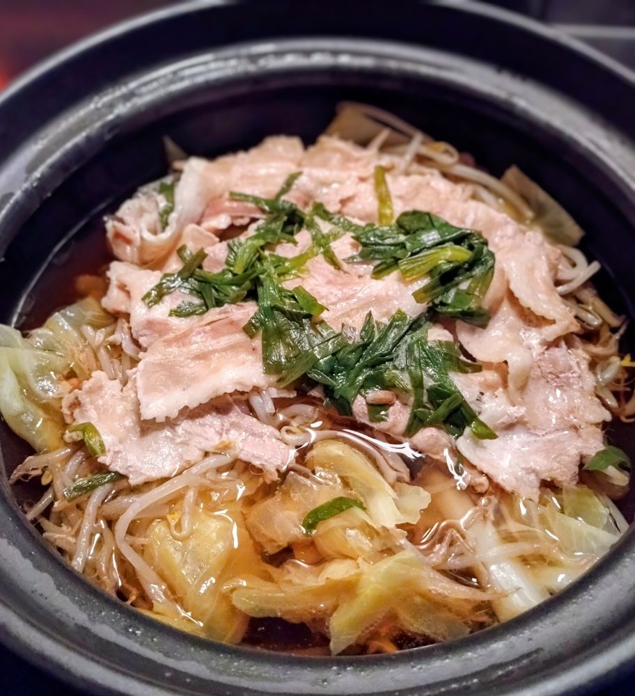 土鍋に入った和風出汁の鍋物の写真
豚バラキャベツもやしニラなどが入っている