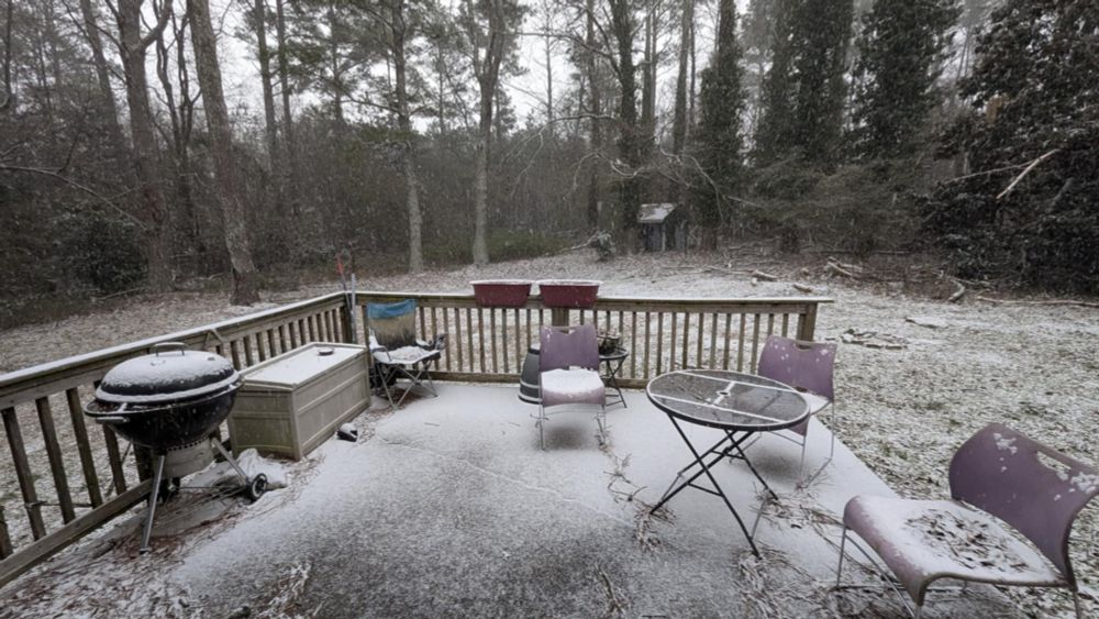 Backyard patio near Atlanta with falling snow and snow on the ground.