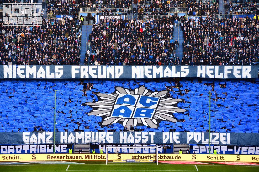 HSV fans doing a giant ACAB tifo, with text saying "Niemals Freund Niemals Helfer Ganz Hamburg hasst die polizei" which translates into "Never a friend, never a helper. All of Hamburg hates the police."