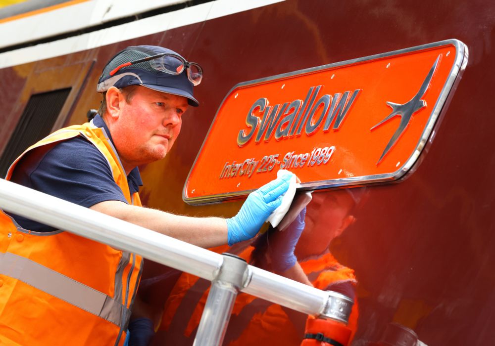 Newly affixed Swallow name plate on 91106 being polished by a colleague wearing PPE in Neville Hill depot.