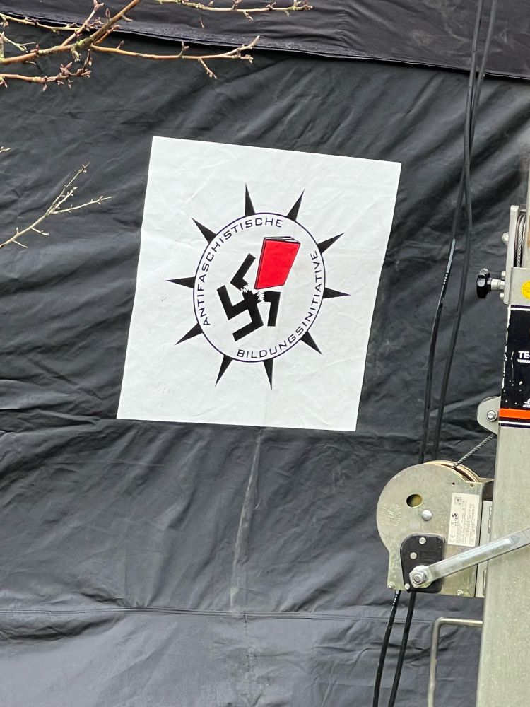 Das Logo der Antifaschistischen Bildungsinitiative. Ein Hakenkreuz wird von einem Buch zerbrochen.