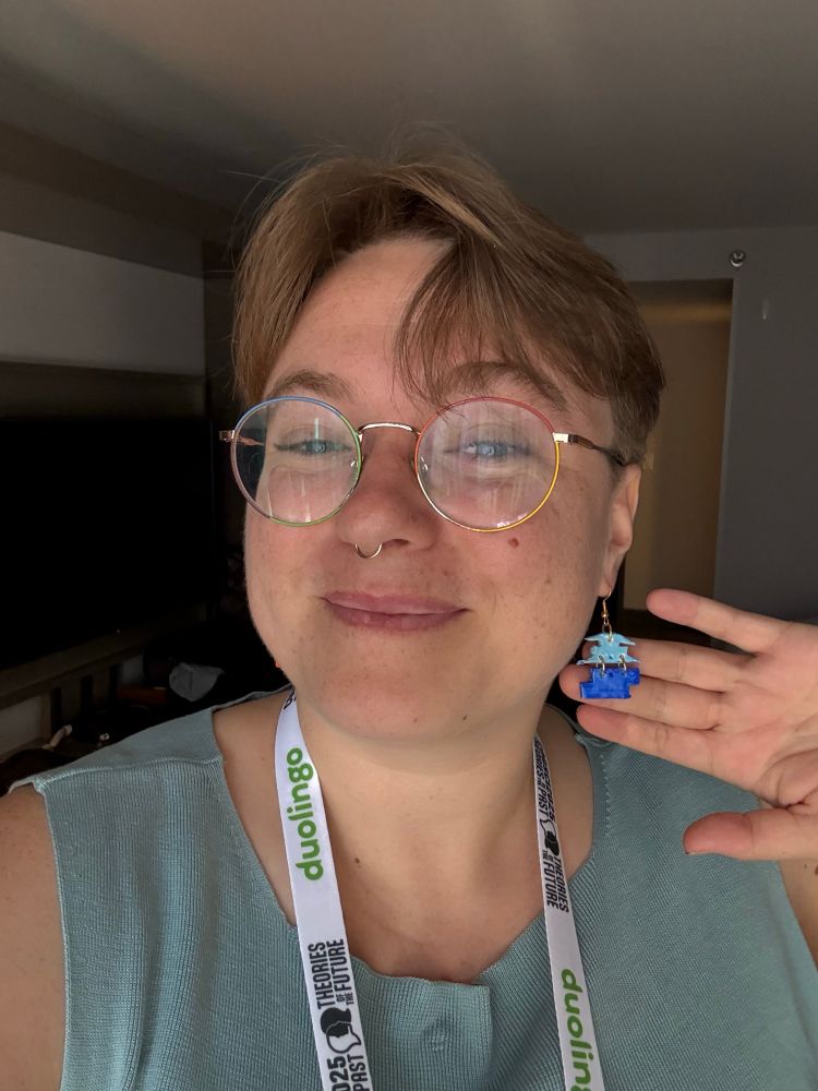 a picture of me wearing a blue shirt. I’m showing off a pair of earrings that are two shapes stacked on top of each other.