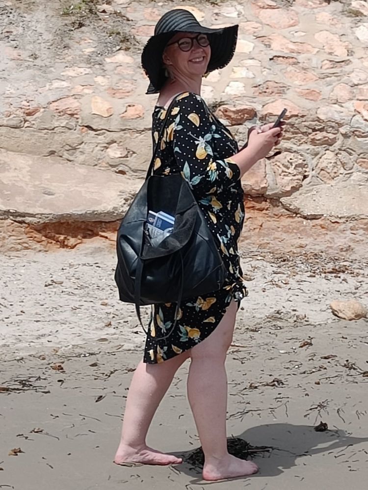 Nainen uimarannalla mustassa mekossa. 