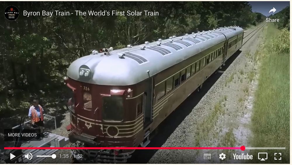 An old 1950s style maroon and cream train of 2 carriages. There are solar panels on the roof. 