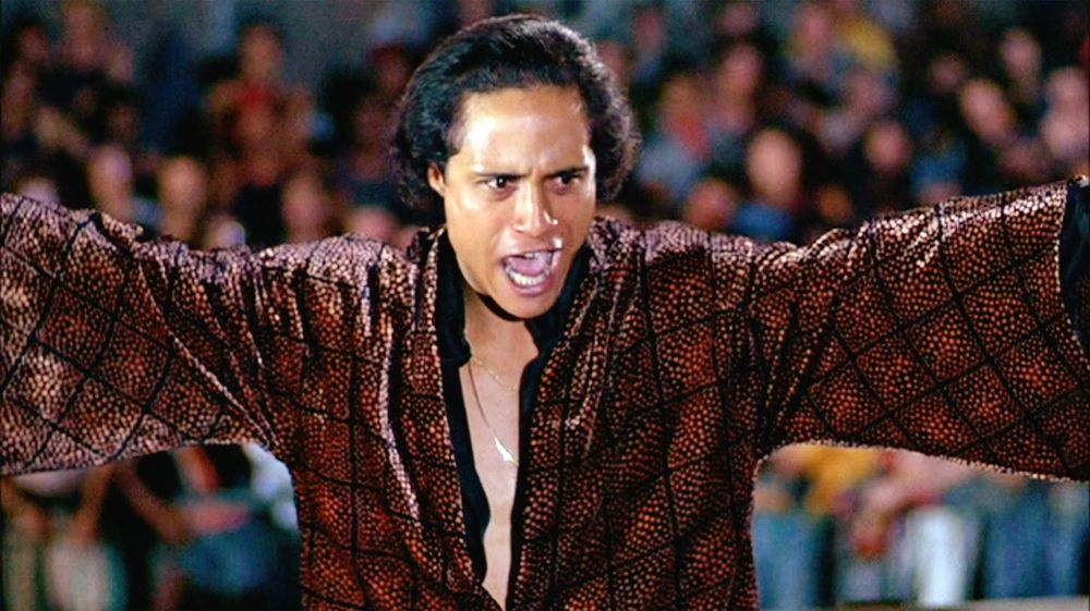 Dark haired young man in long sleeved shirt with the zipper open gives a speech before a huge crowd. (The character of Cyrus from the film The Warriors)