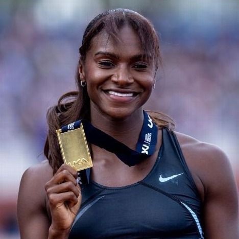 A young woman with long dark hair and wearing an athletics top poses with a gold medal hung around her neck.