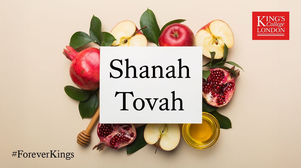 A flat lay arrangement featuring pomegranates, apples, honey, and a jar of honey, with the text ‘Shanah Tovah’ displayed in the center.