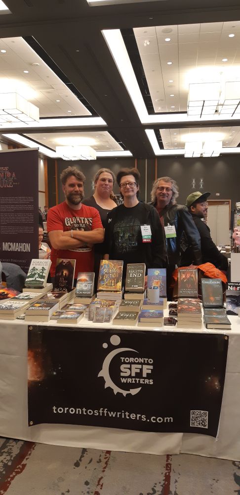 4 people stading behind a table full of books