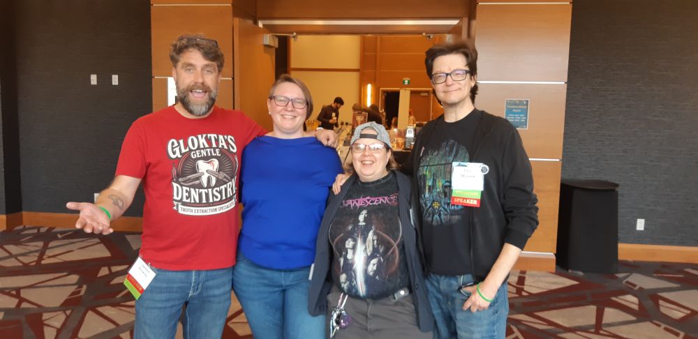 4 smiling people standing, looking at the camera