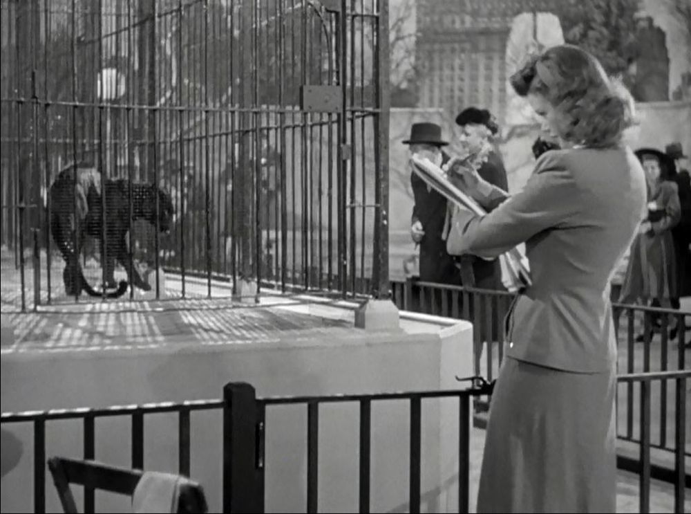 Scène du film "La Féline" ("Cat People" en VO) de Jacques Tourneur, avec Simone Simon.
On y voit une femme esquisser un dessin face à une panthère noire en cage.