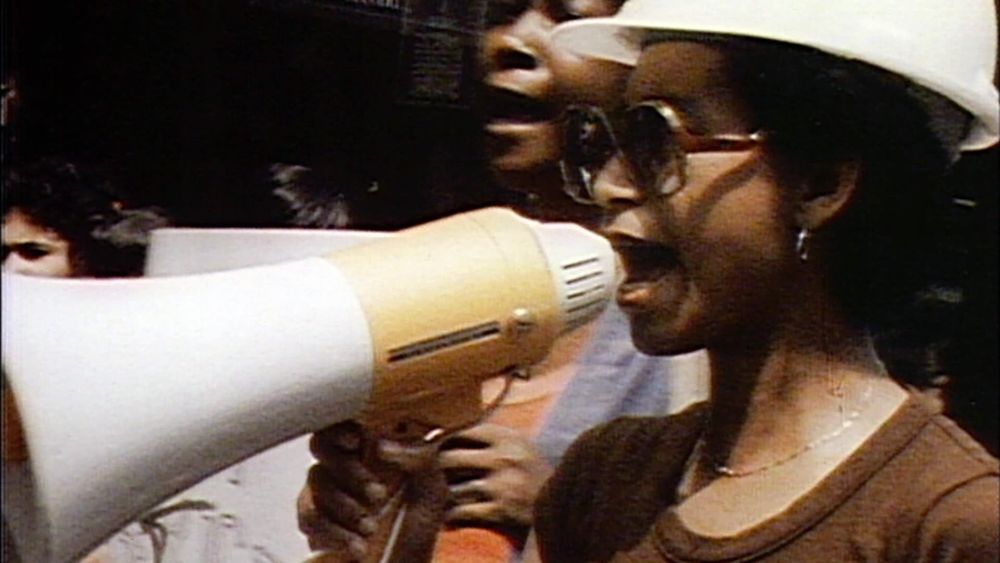 Scène du film "Born in flames" de Lizzie Borden.
On voit une femme avec un casque de chantier crier dans un mégaphone. 