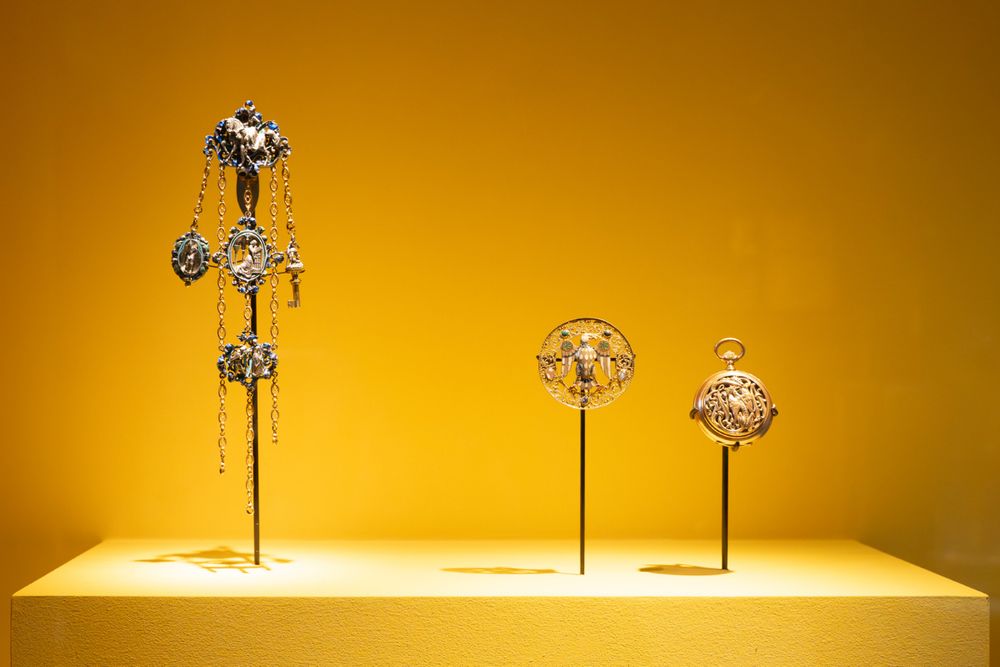 Vitrine exposant des bijoux et les accessoires du 19e siècle inspirés du Moyen Âge : une châtelaine "troubadour", une broche à l’aigle et une montre au combat d’animaux chimériques