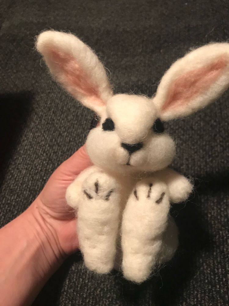 White needle felted bunny with large feet and pink ears