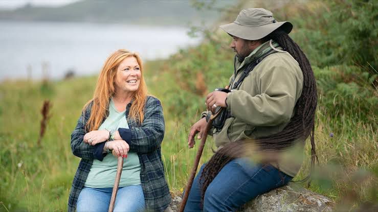 Hamza and his lovely red haired lady neighbour sitting together, smiling at one another next to the water, in the hope of seeing Otters.