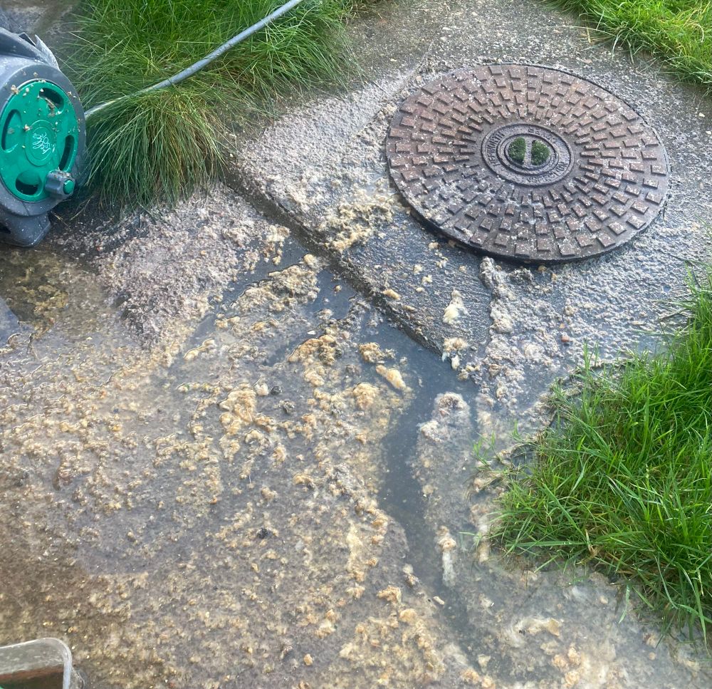 Manhole cover has been breached by a build up of sewage, toilet paper and god knows what else..it’s people sewage and it is gross