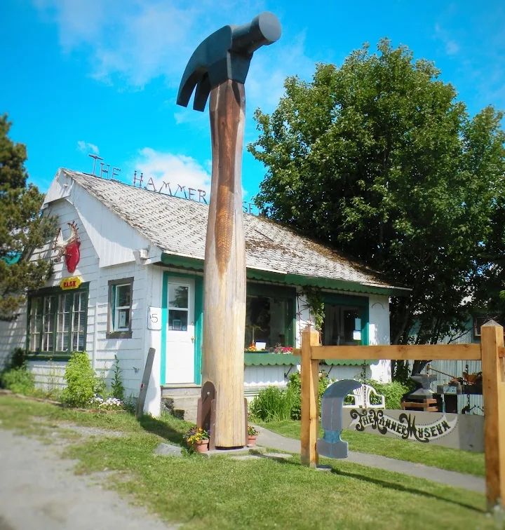 Photograph of a giant hammer in front of the Hammer Museum in Haines Alaska. The Museum occupies all the rooms of a small house.