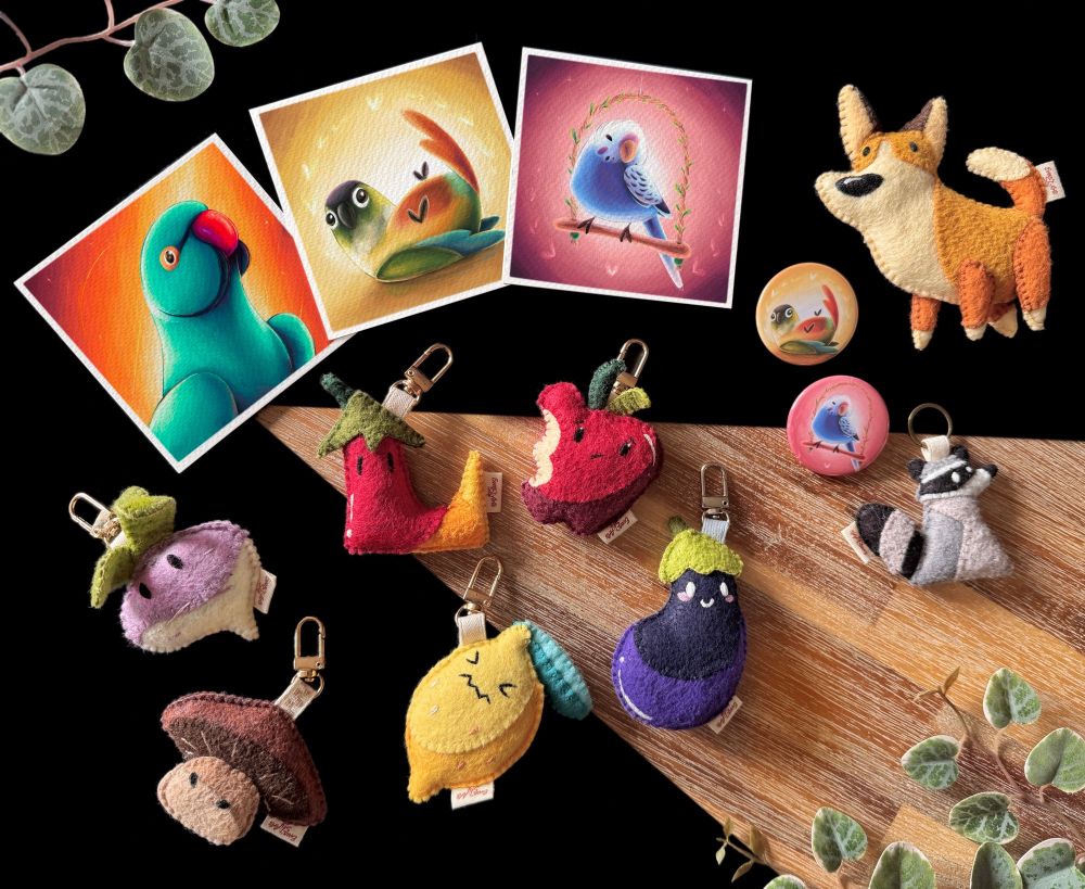 Picture of some products that are currently available on my website: 3 mini prints featuring an Indian ringneck, a green cheek conure, and a budgies two button badges matching the motive of the conure and budgie prints; a small corgi felt plushie; a raccoon keychain; and 6 fruits and vegetable themed bag charms!