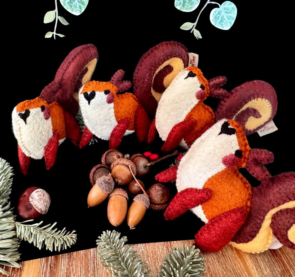 Four squirrel felt plushies hanging out around a pile of acorns. They’re looking at you. They want your acorns. You should surrender.