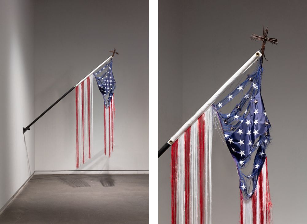 Moral Disengagement (2014-2017) is the name of this piece that is a disassembled American flag that has pieces hanging in very fine strips from a flag pole. The stars area with the blue background is also ripped, a woven cross desperately tries to hold the flag together at the corner