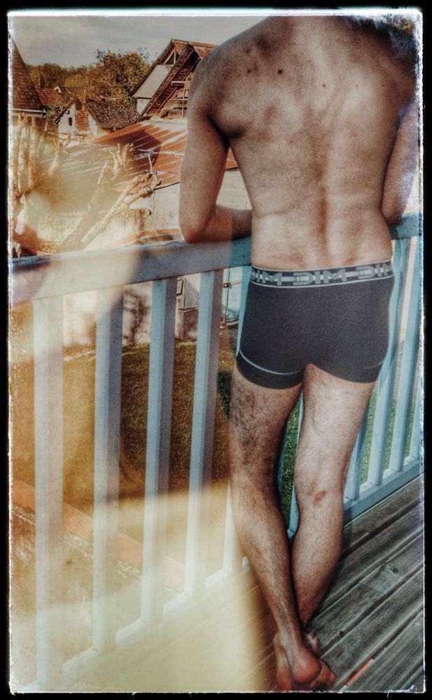 Homme en boxer accoudé à un balcon avec en surimpression le visage d'une femme magnifique.