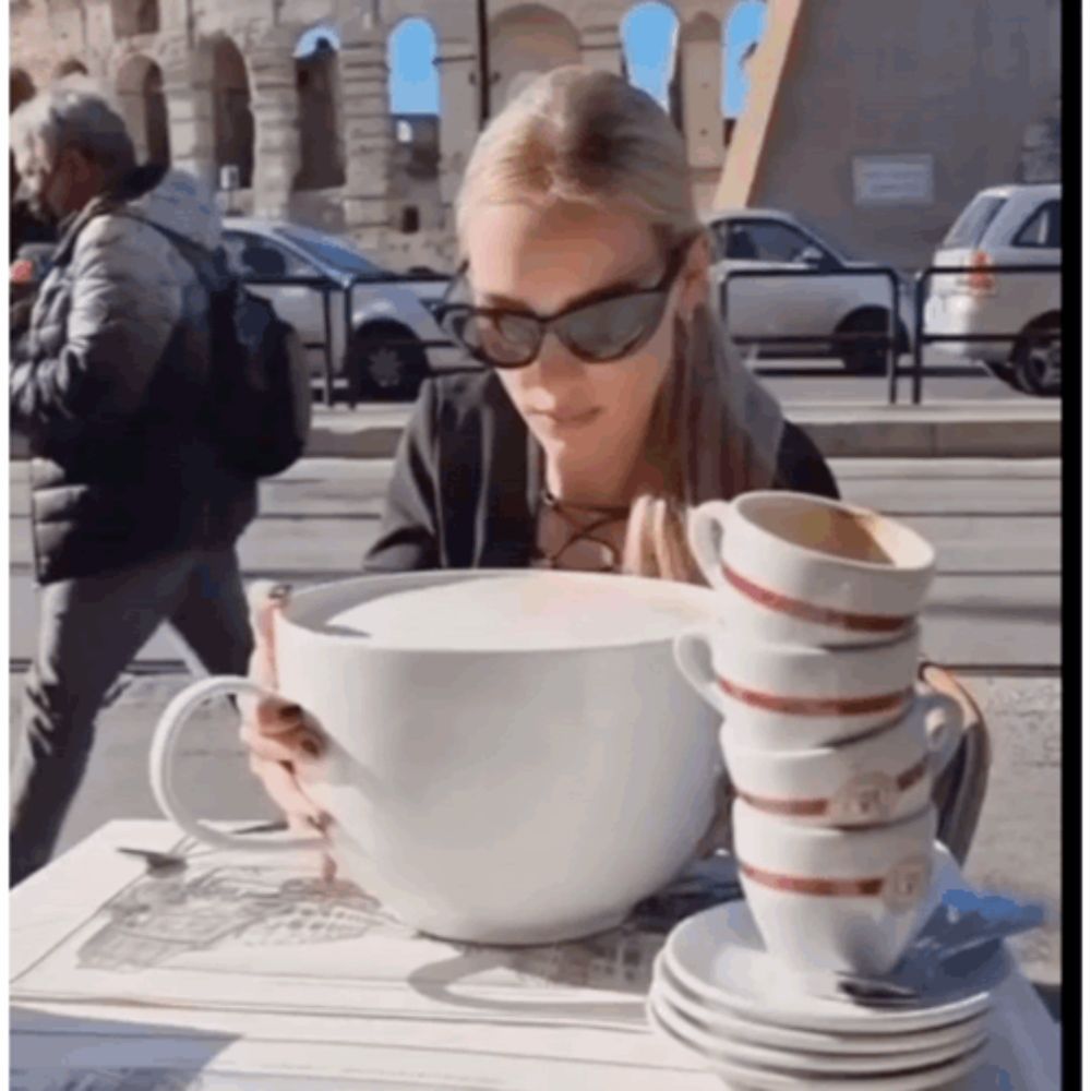 a woman is sitting at a table with a stack of coffee cups on it