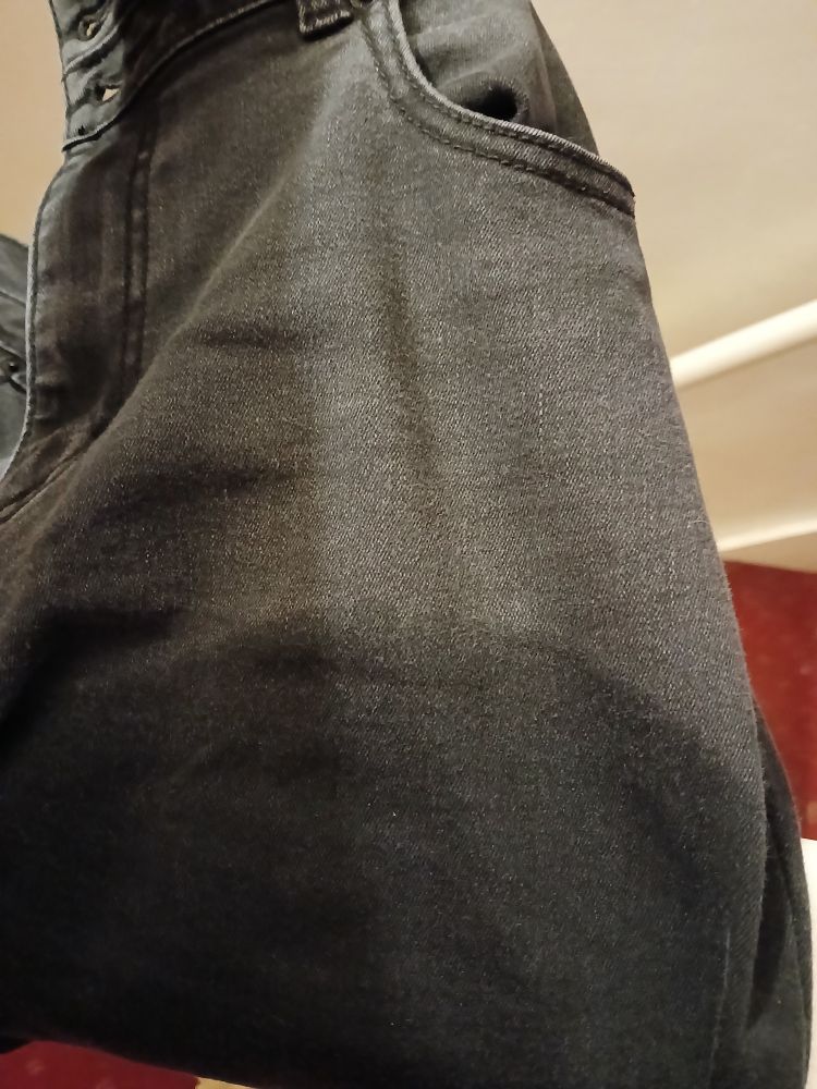 a picture showing the top portion of a pair of jeans draped over a banister. They are almost entirely soaked entirely with water.
