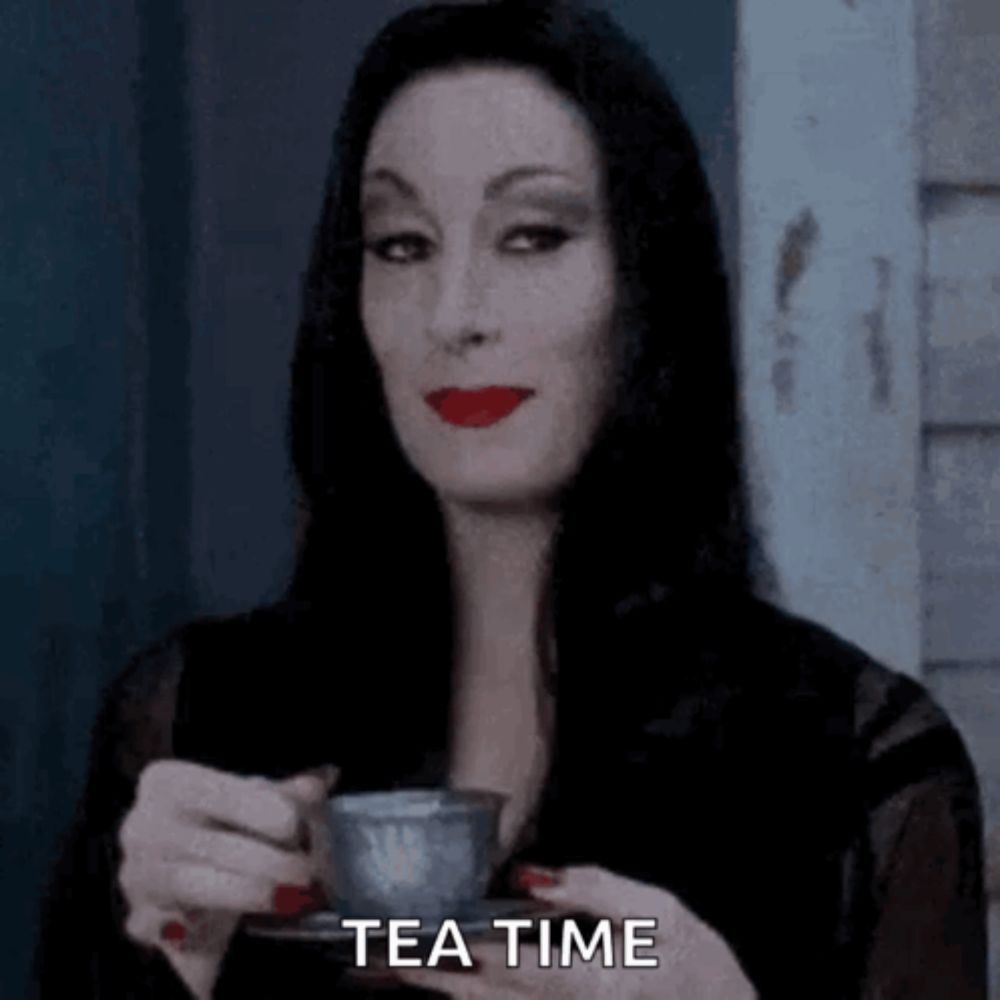 a woman in a black dress is holding a cup of tea and saying `` tea time '' .