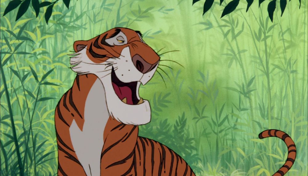 Screen shot of the character Shere Khan in the Walt Disney version of Jungle Book. Mouth is open in the middle of dialog, around him is lush green of what appears to be bamboo and other jungle foliage.