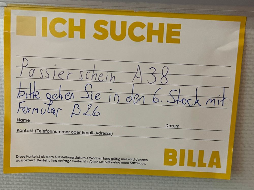 Ein Billa „Ich suche“ Zettel an der Anschlagtafel. Darauf steht „Passierschein A38“. Eine andere Person hat geantwortet „bitte gehen Sie in den 6. Stock mit Formular B26“