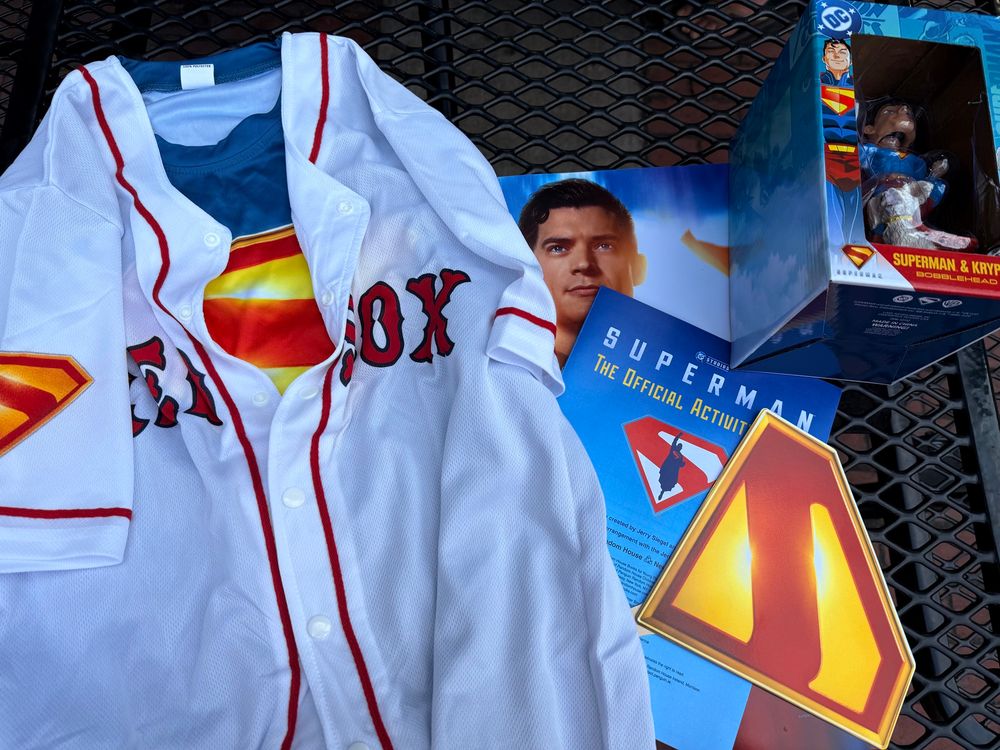 Superman shirt underneath a Red Sox jersey. Superman poster, activity book, fan, and bobble head. 