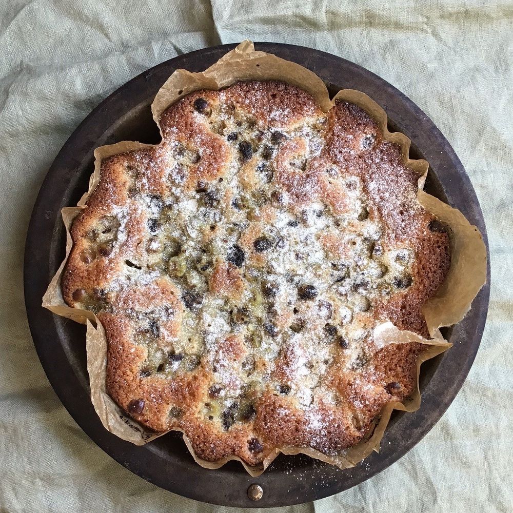A Netherton Foundry pie dish containing a gooseberry almond pudding, sitting on a linen tabelcloth