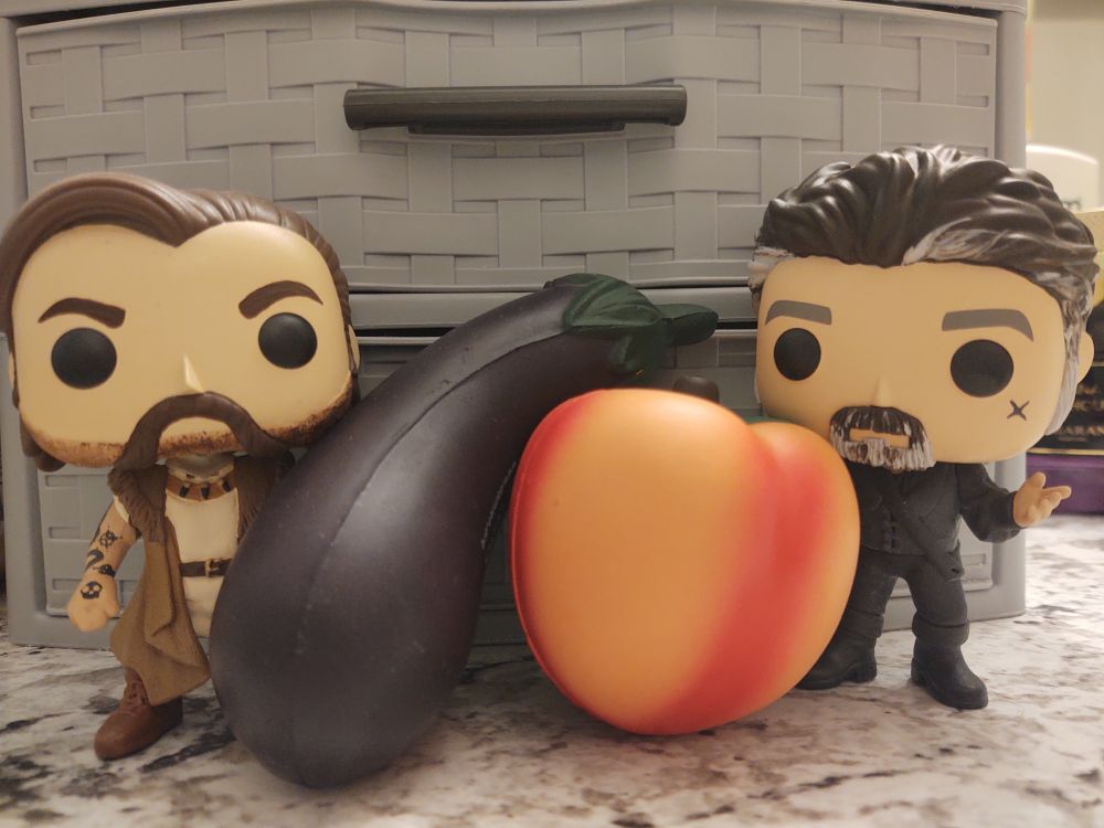 Jack and Izzy custom funko pops by HamilPOP. In between them are a stress ball eggplant resting on a stress ball peach