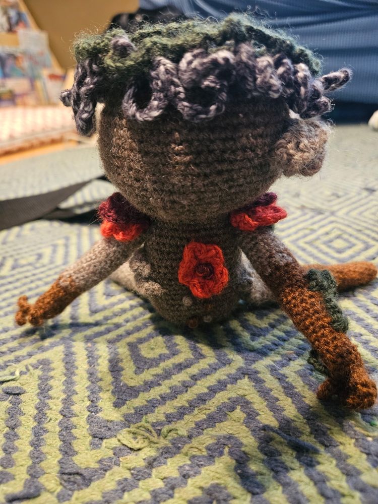 Picture of a crochet Adne Sadeh vegetable man leaning forward, showing off it's flowers