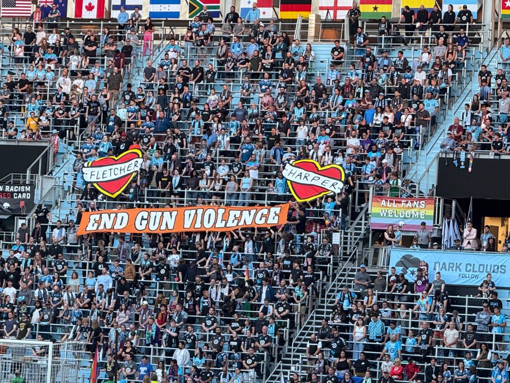 Sign in the supporters section at Allianz Field says “End Gun Violence” with names of children lost in the recent Minneapolis shooting, Fletcher and Harper. 