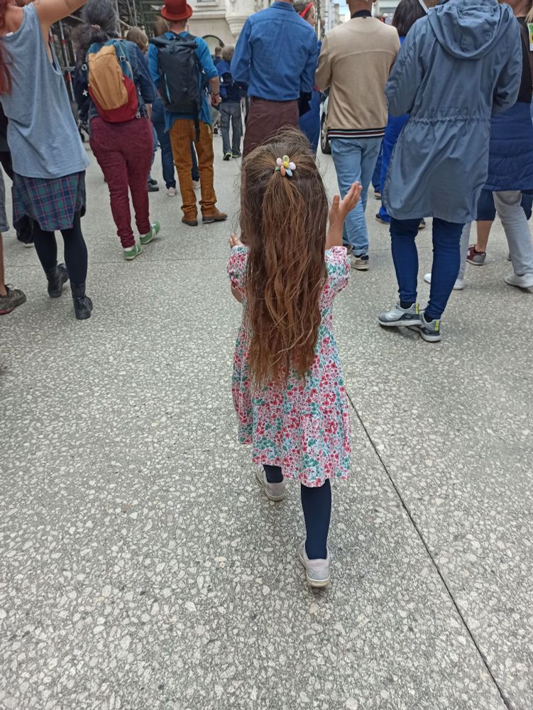 Photo d'une petite fille de dos qui applaudit joyeusement dans le cortège de la manifestation contre l'extrême droite le 15 juin