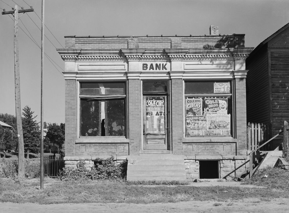Arthur Rothstein photographed this failed bank in Haverhill, Iowa, in September 1939. The large window to the left of the entrance door appears to be broken. Posters for the Cole Bros. circus cover the door and the large window to its right. The Social Security Administration website’s history section features Rothstein’s photo, with the following text: “Many smaller banks, such as this one in Haverhill, Iowa, lacked sufficient reserves to stay in business and became no more than convenient billboards. Many of the small banks had lent large portions of their assets for stock market speculation and were virtually put out of business overnight when the market crashed. In all, 9,000 banks failed--taking with them $7 billion in depositors' assets. And in the 1930s there was no such thing as deposit insurance--this was a New Deal reform. When a bank failed the depositors were simply left without a penny. The life savings of millions of Americans were wiped out by the bank failures.”