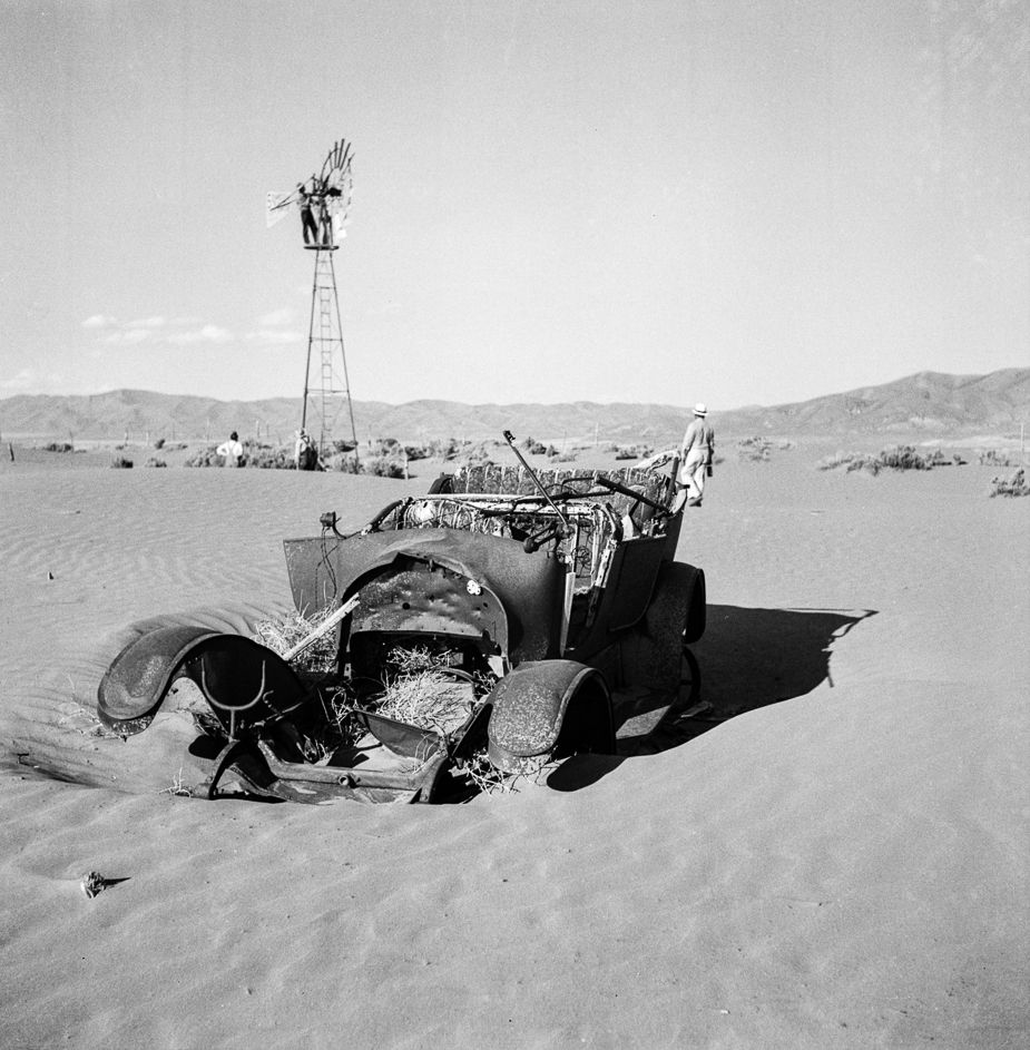 Failed farm: Wilbur Staats’s March 1937 photograph shows what’s left of an abandoned farm in Idaho. A derelict auto sits half-buried in dirt and sand in the foreground, its engine scavenged. Several men examine the windmill, with one having climbed to the platform to take a closer look. A fence line appears in the background, but there is no evidence of a dwelling.