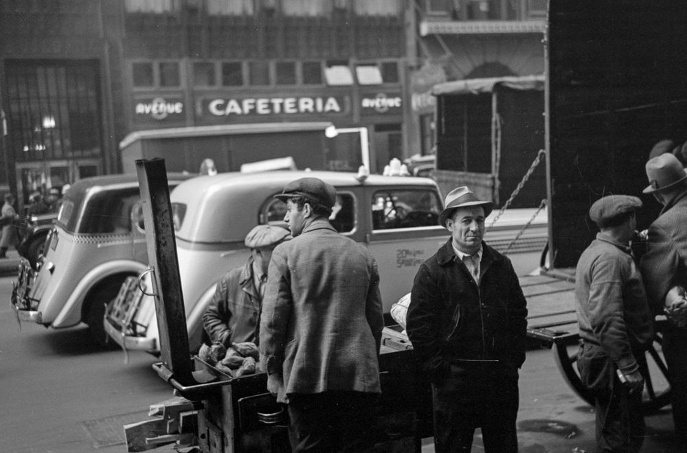 Russell Lee captured a busy day on Manhattan’s Eighth Avenue in November 1936. Taxicabs and trucks jam the street, workers unload a wagon, a vendor sells from his cart and the avenue’s namesake cafeteria beckons across the avenue.