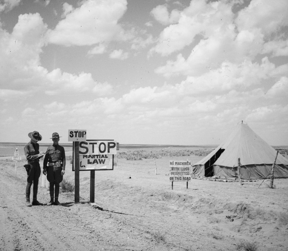 Closing the border: Two Colorado National Guardsmen enforce martial law to prevent migrants from other states and Mexico from crossing the state’s southern border. With a tent for their barracks, they stand in the road, wearing sidearms, next to a sign declaring “STOP Martial Law.” According to the "Colorado Encyclopedia," “For ten days in 1936, Colorado governor Edwin ‘Big Ed’ Johnson declared martial law in the state, which allowed him to close Colorado’s southern border . . . Amid record unemployment during the Great Depression, Johnson closed the border because he feared an ‘invasion’ of 'alien and indigent persons’ who would take scarce jobs from white Coloradans.”